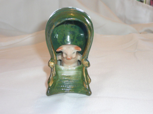 This small pig is sitting in a high-backed chair with gilding on the ribbons. I've only seen one other on ebay. 3 1/2" x 1 3/4". Paid $45. Rare.
