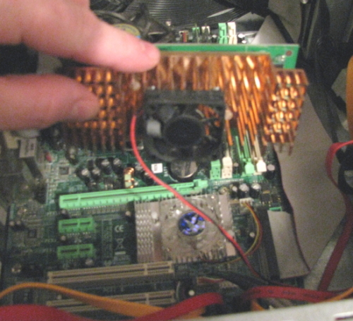 I had to remove the video card to get to the NB heatsink fan.  First I removed the screw securing the card to the back of the case.    [Yes that is an aftermarket 40mm fan stuck to the heatsink on the video card]