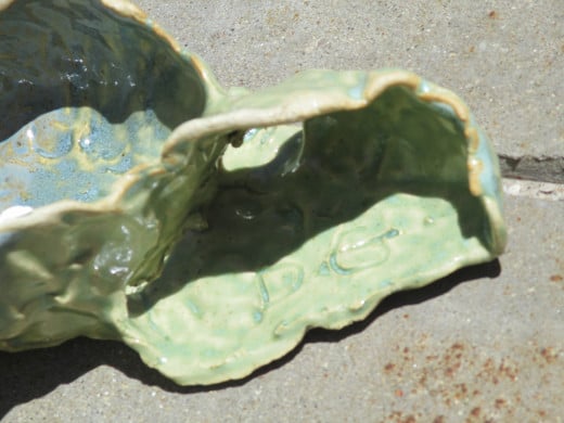 Weird freeform piece of pottery, glazed on one half with celadon glaze.