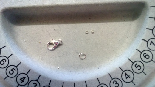 A lobster clasp, two crimps, and an open jump-ring.