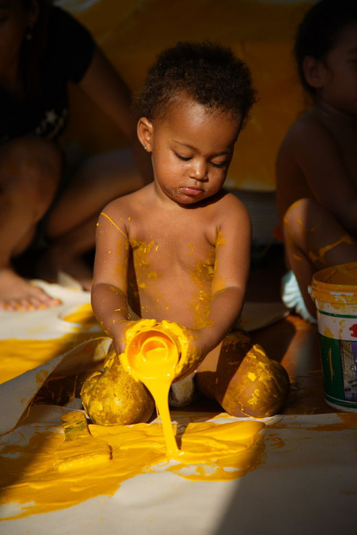 A toddler playing with yellow paint.