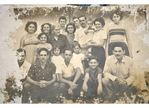 Isabel's father in the black shirt kneeling with his family