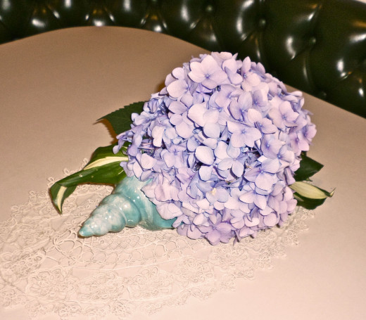 I used Hosta leaves with the Hydrangea bloom in a coordinating vase shaped like a shell.  Finish the look with a hand crocheted doily.