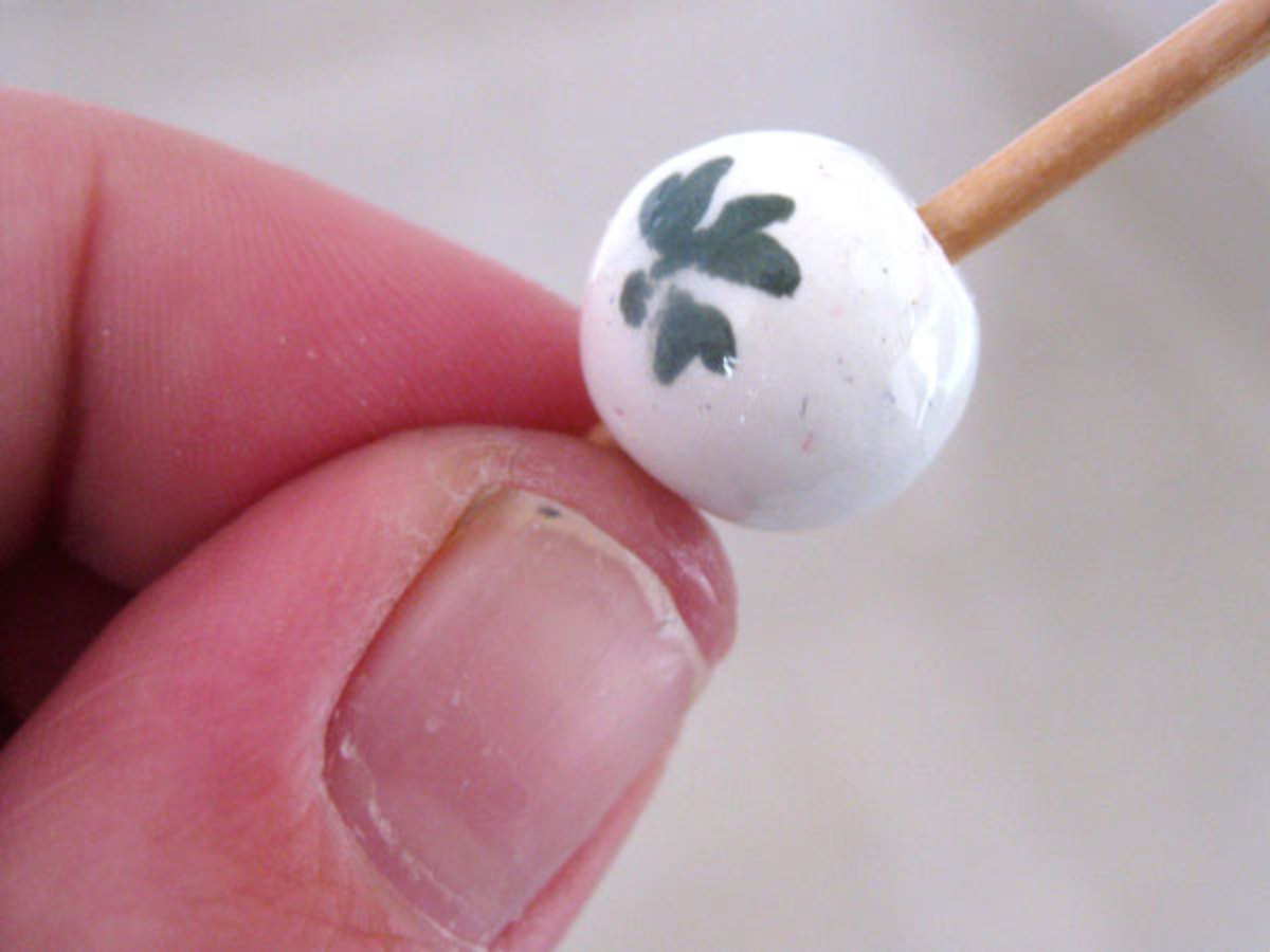Holding a bead on one end while glazing the other on a toothpick.