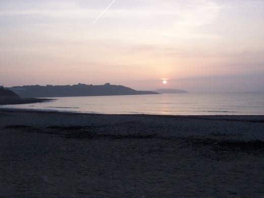 Looking out from Gyllyngvase Beach towards Pendennis Headland at dawn.