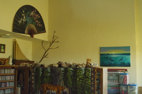 The corner of the room. Fan, dolphin painting, tiger tapestry.