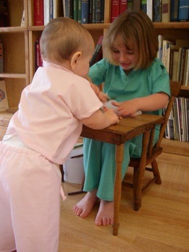 Two children play wearing scrubs.