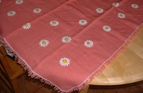 Vintage tablecloth with ribbon flowers and fringed edges.