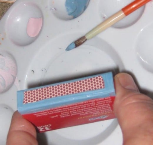 Paint the edges of the matchbox where the scrapbook paper may not easily cover.