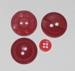 Red plastic buttons with carved designs, except that little feller. He's just cute.