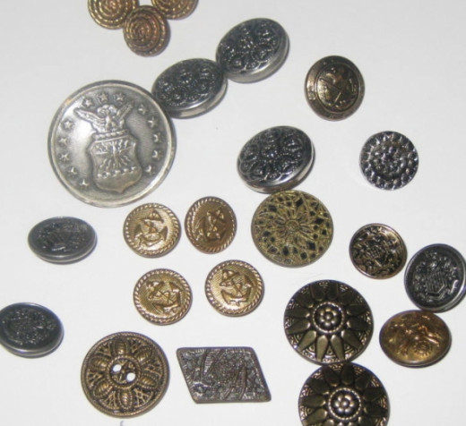 An assortment of metal buttons. All of these metal buttons are decorative and all but one has a shank at the back so all of the button's beauty shows.