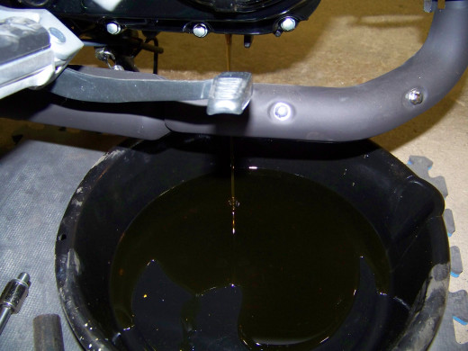 Let the oil drain into the pan. Move the Grom to an upright position until the remaining oil trickles out.