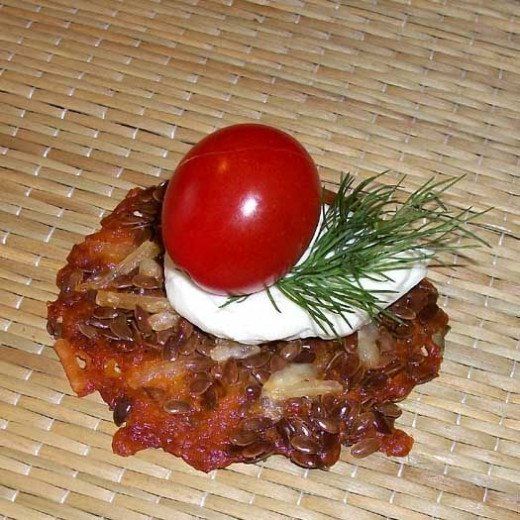 Flax seed cheese cracker topped with goat cheese, grape tomato, and fresh dill