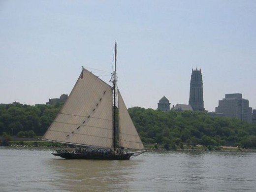 Photo of the sloop Clearwater sailing south on the Hudson River, past Manhattan's Grant's Tomb and Riverside Church