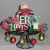 Santa holding a "Merry Christmas" sign on the black wire cake stand.