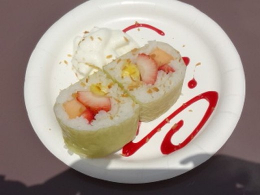 Frushi - Fresh Strawberries, Pineapple and Cantaloupe, rolled with Coconut Rice, atop a Raspberry Sauce sprinkled with Toasted Coconut and Whipped Cream