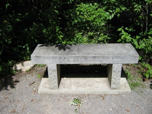 Donated bench beside boulder inscribed with, "Make this world a little better and more beautiful because you live in it."