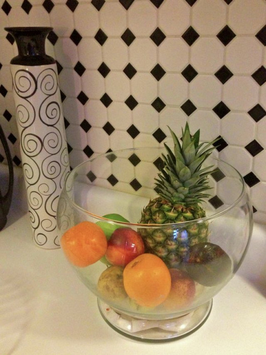 A glass bowl holds fruit. It's decorative and seems to 'disappear' giving the illusion of space