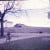 Photo of the Iowa Farm - Garage on left; Corn crib on hill. Brother on bicycle.