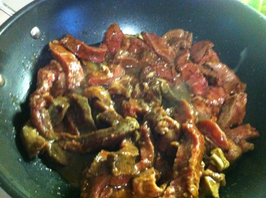 Add the steak strips along with the garlic and marinade into the heated wok, and stir-fry.