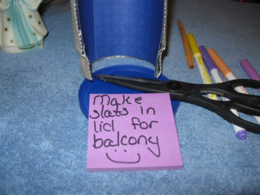 Cut out two notches for the upper stack in the lid to make the floor of the top stack balcony. Place the doorway opening an inch or so into the notches and glue it down. Use a lot of glue to be sure it will hold the weight of your doll.Let's do anoth