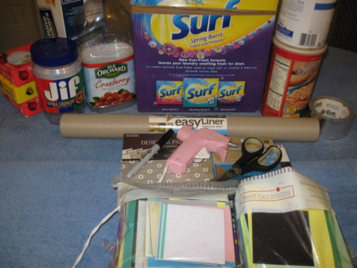 Needed: 1 clean, empty laundry soap box, two small boxes, shelf paper, colored paper, doilies, pony beads, prong studs, glue gun, ribbon, 1 chain, Mod Podge and some bling.