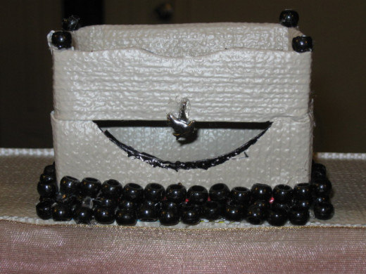 Pony beads and a dove charm are glued down to the turret. A dowel rod, colored black with a Sharpie marker was glued directly behind the turret. The chain that is glued to the front of the draw bridge is wrapped around the ends when open, and around 