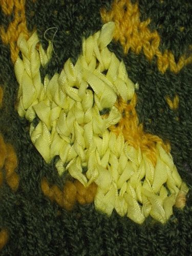 A yellow ribbon knit in amongst some acrylic yarn.