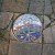 This is one of several tile work plaques set into the crazy paving. It uses recycles pottery to make a mozaic and is both pretty and interesting.